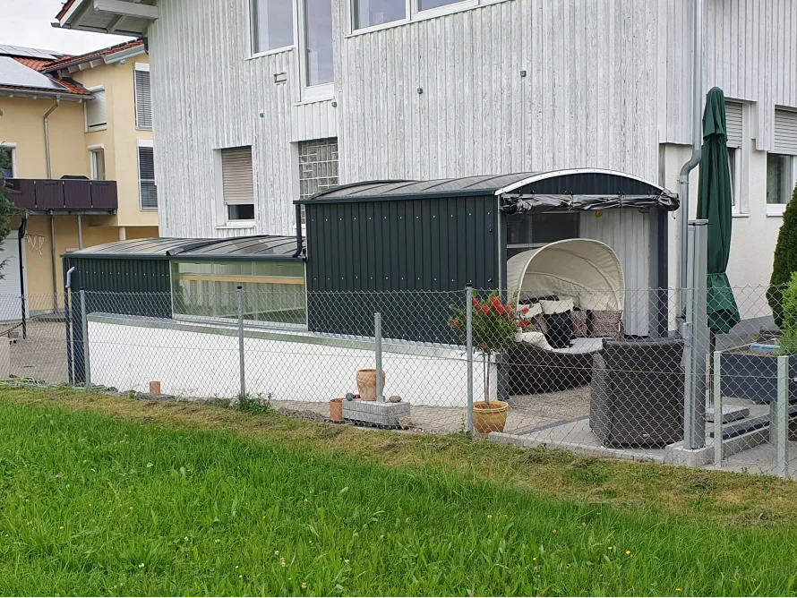 Eine dunkelgrüne Poolüberdachung mit Lounge-Möbeln auf einer Terrasse.