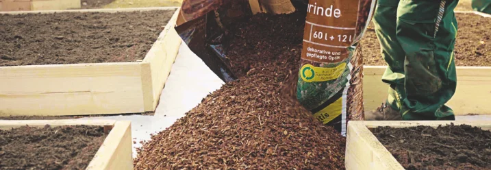 Person schüttet Rindenmulch aus einem Sack