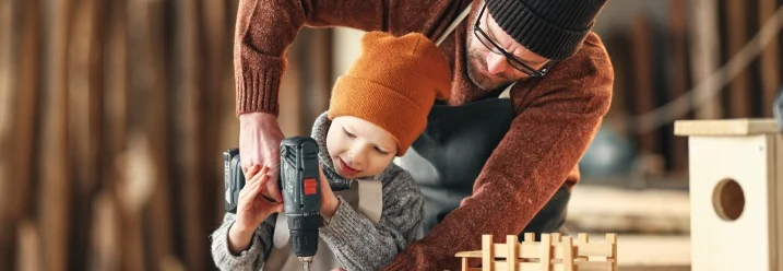 Vater und Sohn bohren gemeinsam in ein Stück Holz