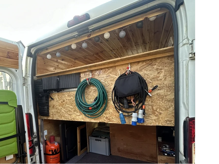 Ein aufklappbarer Transporter mit einem selbstgebauten Stauraum aus Holz an der Innenseite der Türen.