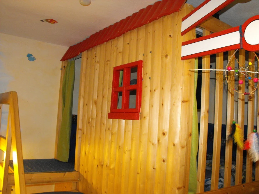 Spielhaus aus Holz mit rotem Dach