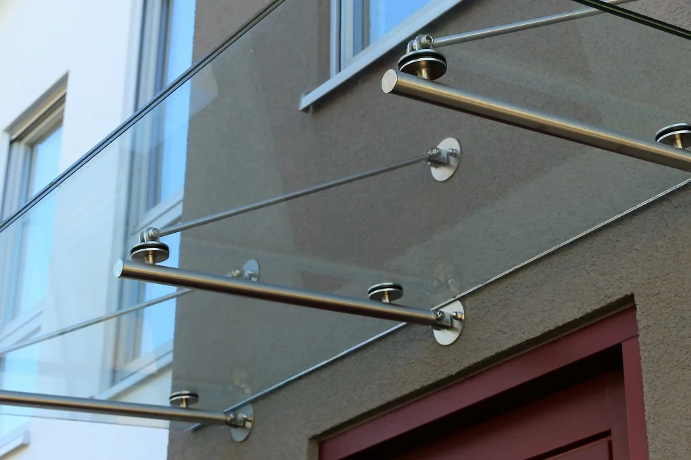 Ein Vordach aus Glas und Metall über einer Tür.