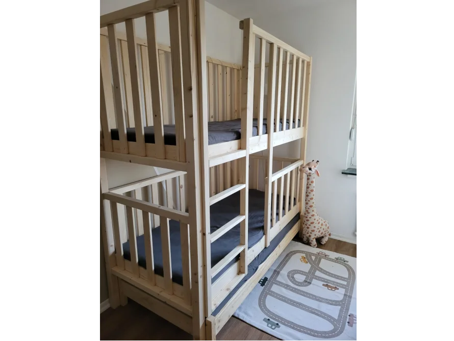 Ein Hochbett aus hellem Holz mit Rautenmuster-Teppich.