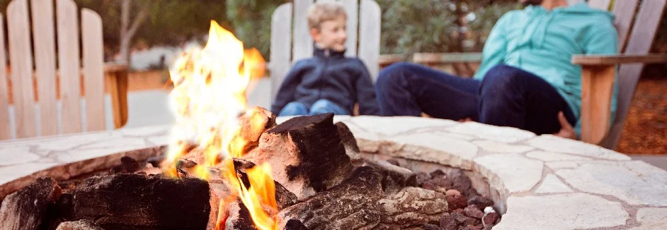 Zwei Personen sitzen an einer Feuerstelle