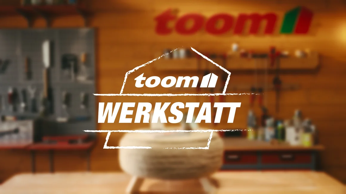 Unscharfe Werkstatt mit Werkzeug an der Wand. Logo der toom Werkstatt