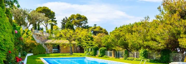 Einbaupool in einem Garten mit Rasenfläche und Bäumen.