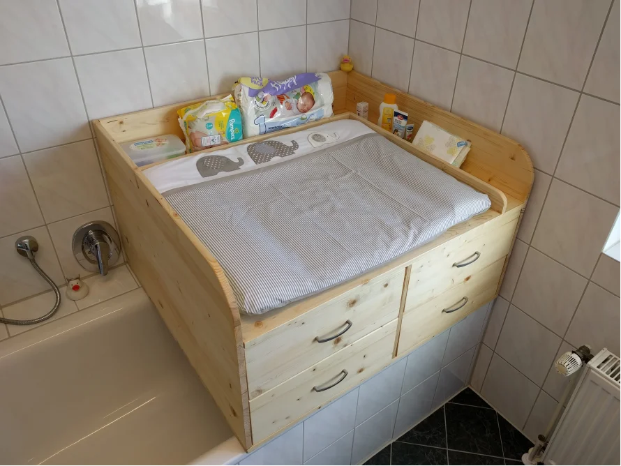 Ein Wickeltisch aus Holz über einer Badewanne.