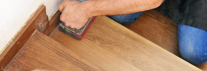 Person schleift Holztreppe mit Schleifgerät