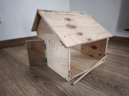 Ein kleiner Holzstall für Kinderspielzeug auf einem Holzboden.
