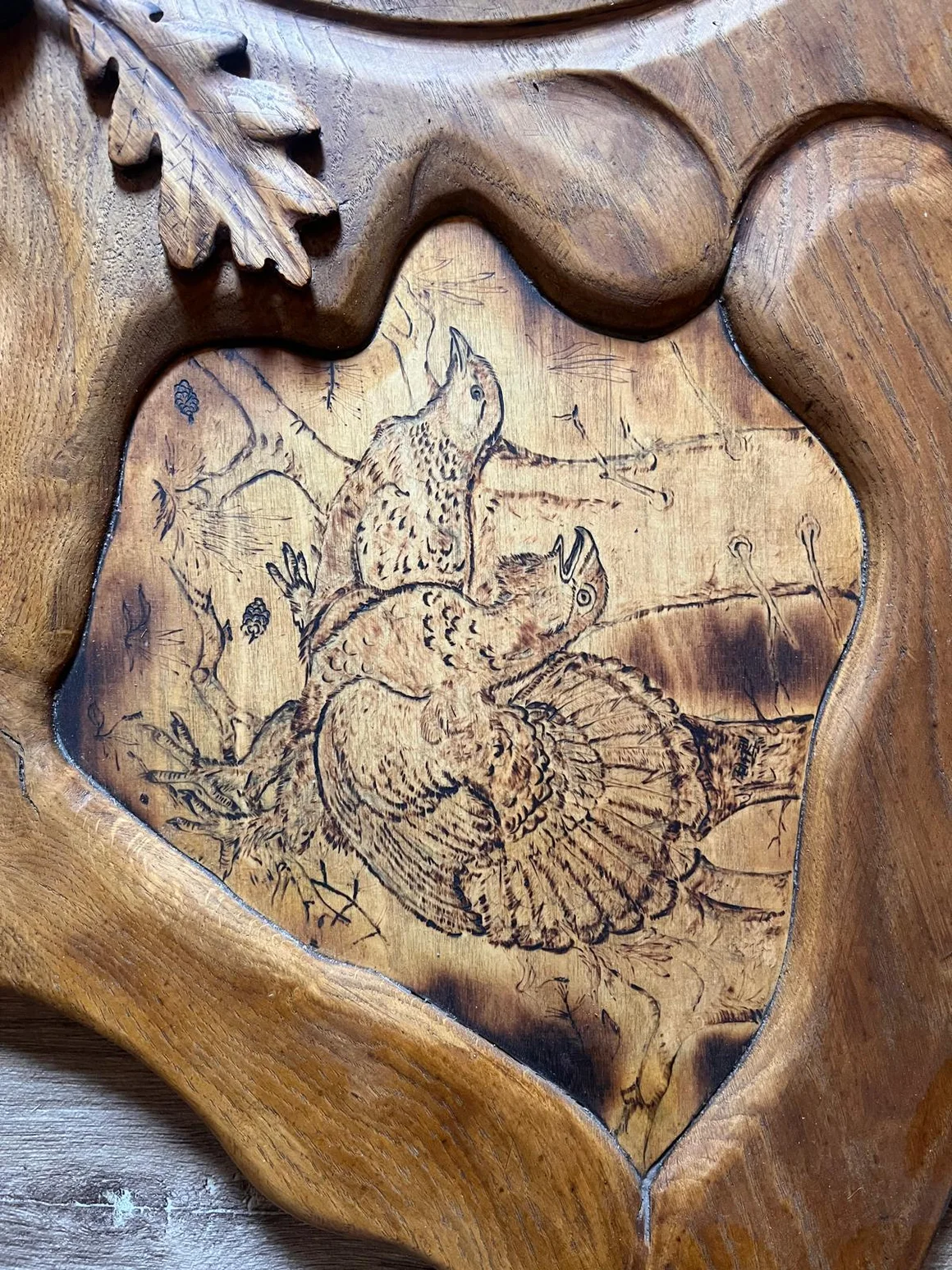 Nahaufnahme einer Holzschnitzerei mit einer Brandmalerei von zwei Vögeln.
