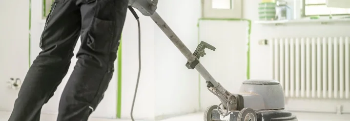 Person schleift Betonboden mit Maschine