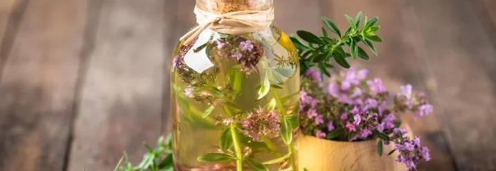 Glasflasche mit Thymianöl und frischen Zweigen