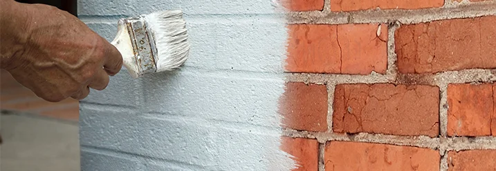 Person streicht Ziegelwand weiß