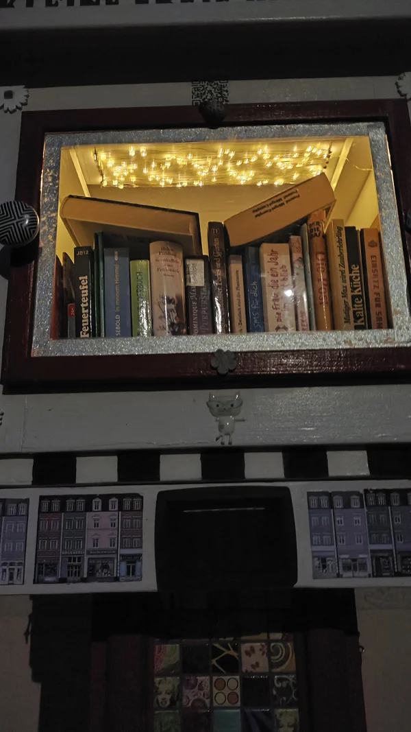 Ein verzierter und beleuchteter Bücherschrank bei Nacht.