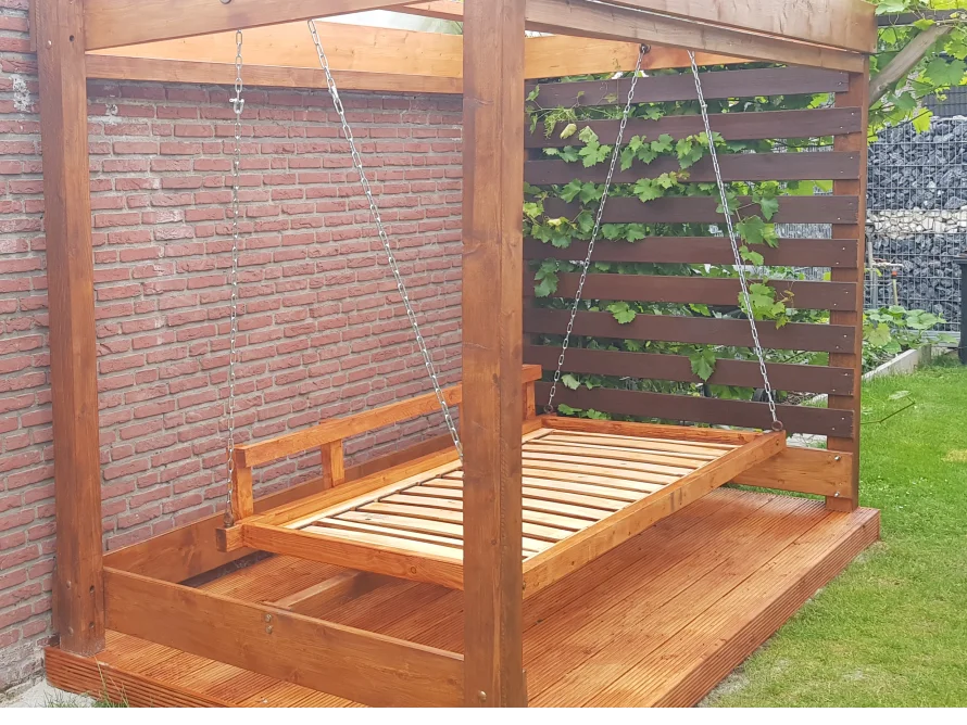 Hölzerne Schaukelliege unter Pergola