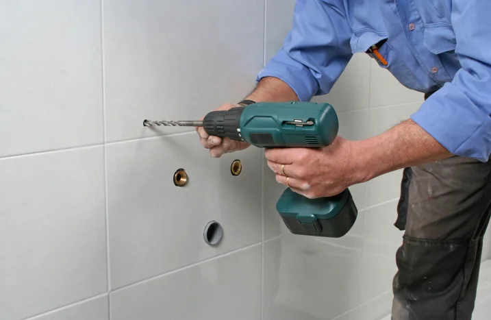 Person bohrt mit Bohrmaschine in Fliesen