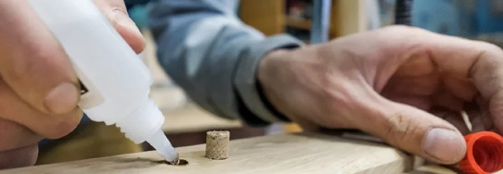Person verklebt Holzdübel mit Klebstoff