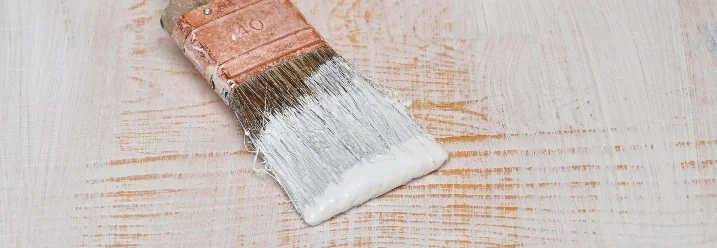 Pinsel mit Grundierung liegt auf Holz