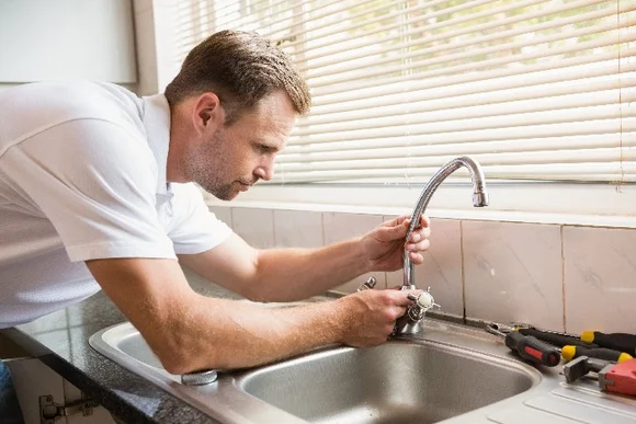 Person repariert Wasserhahn