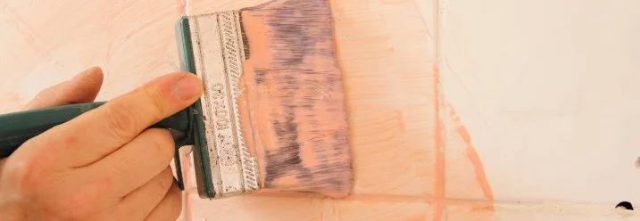 Hand bestreicht Fliese mit Pinsel