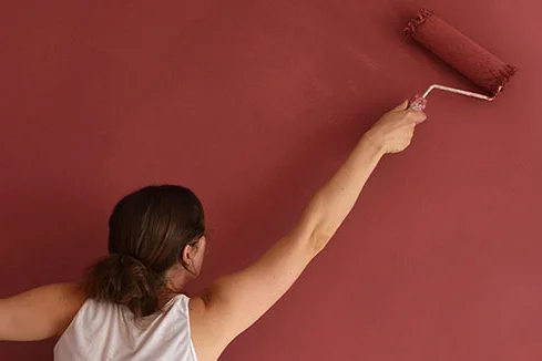Person streicht Wand rot