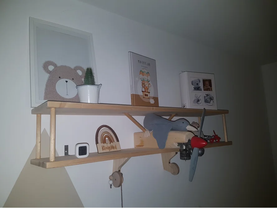 Ein hölzernes Flugzeugregal an einer Kinderzimmerwand.