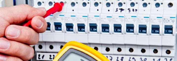 Person prüft Elektroinstallation mit einem Messgerät.