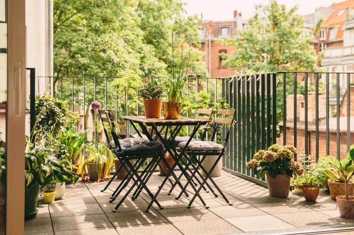 Sonniger Balkon mit vielen Pflanzen und Tisch