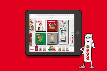 Comicfigur Zolli steht neben der toom-kids App die auf einem Tablet abgebildet ist