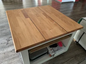 Ein quadratischer Couchtisch mit einer Tischplatte aus Holz und einem weißen Untergestell.