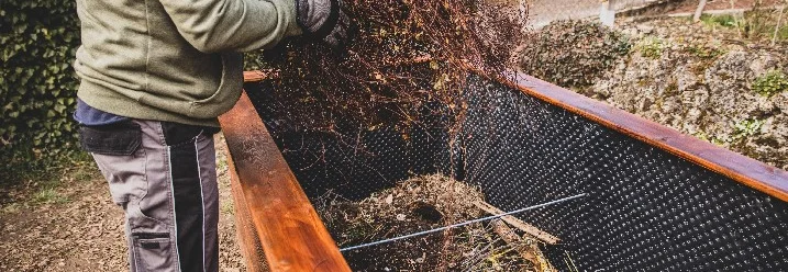 Person füllt Äste in Hochbeet