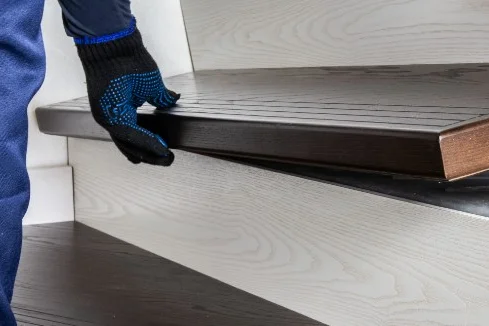 Person montiert Holzstufe auf Treppe