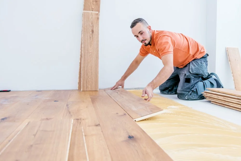 Handwerker verlegt Boden in einem modernen Neubauhaus.