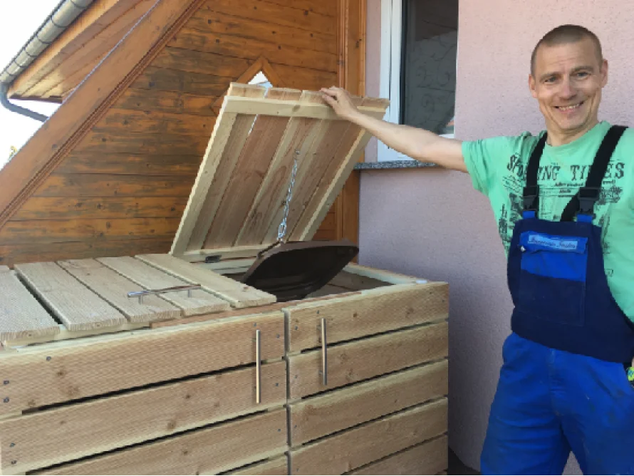 Person präsentiert Mülleimerverkleidung aus Holz