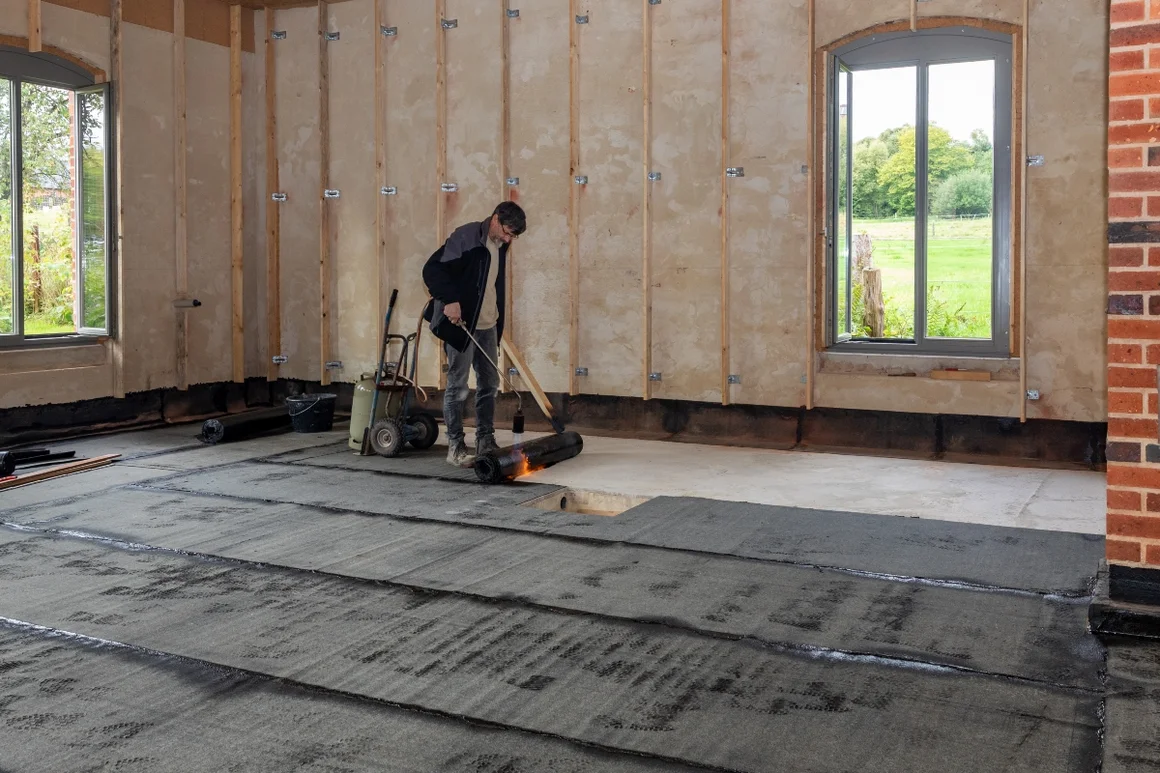 Person bringt Dachpappe mit Gasbrenner an