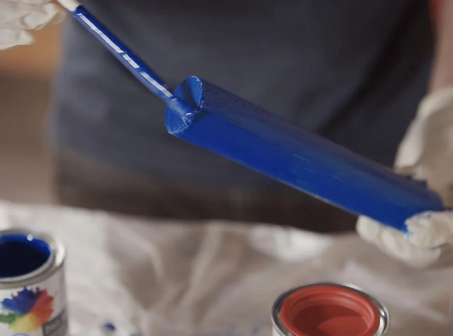Person streicht Holz blau an