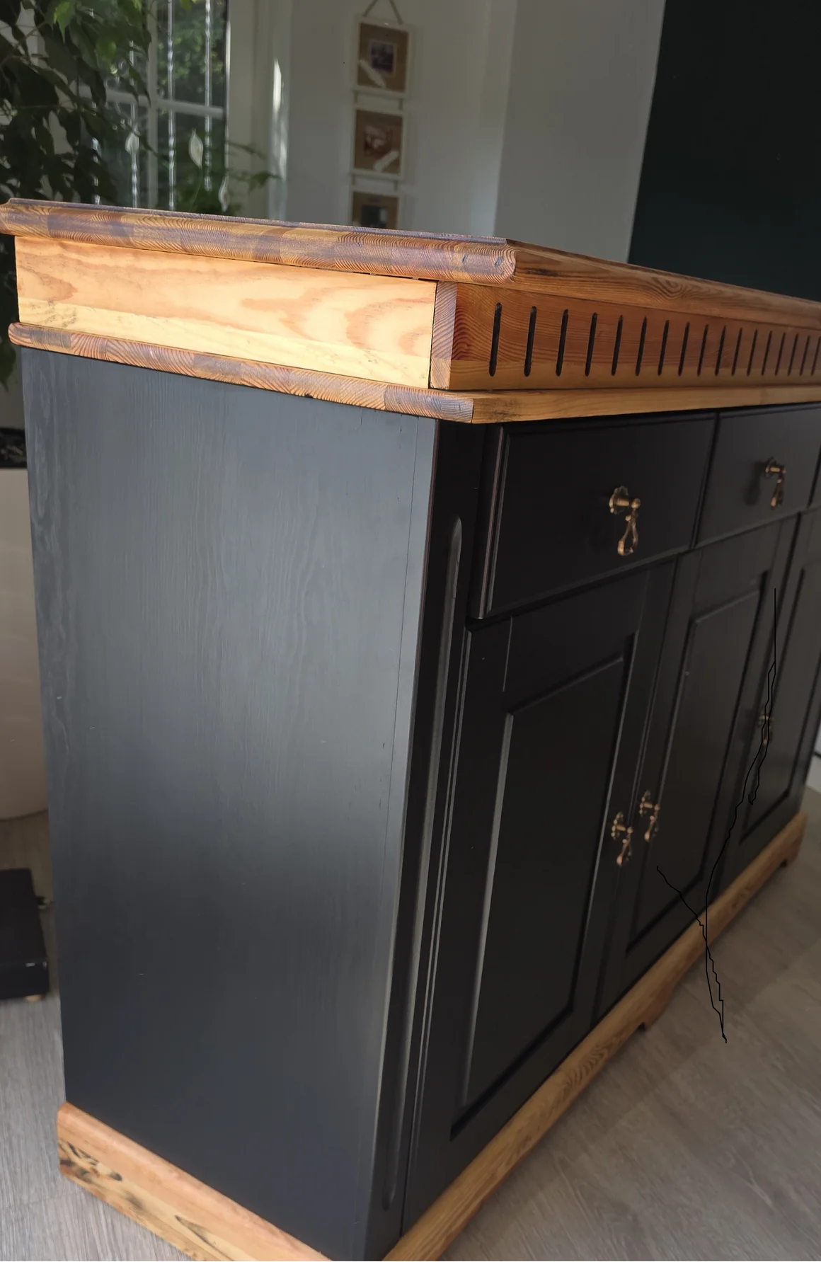 Eine schwarze Kommode mit einer Arbeitsplatte aus Holz.