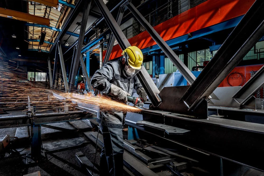 Person bearbeitet Metallträger mit Winkelschleifer