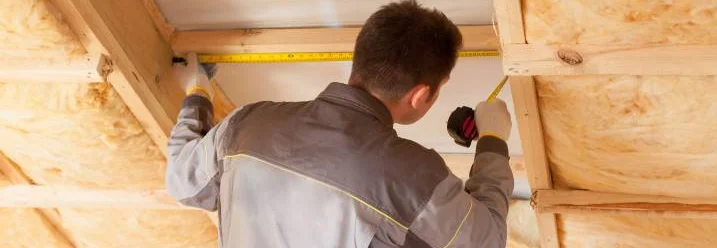 Person misst Dachfenster aus mit Zollstock