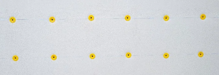 Gelbe Dämmstoffhalter an einer weißen Wand.