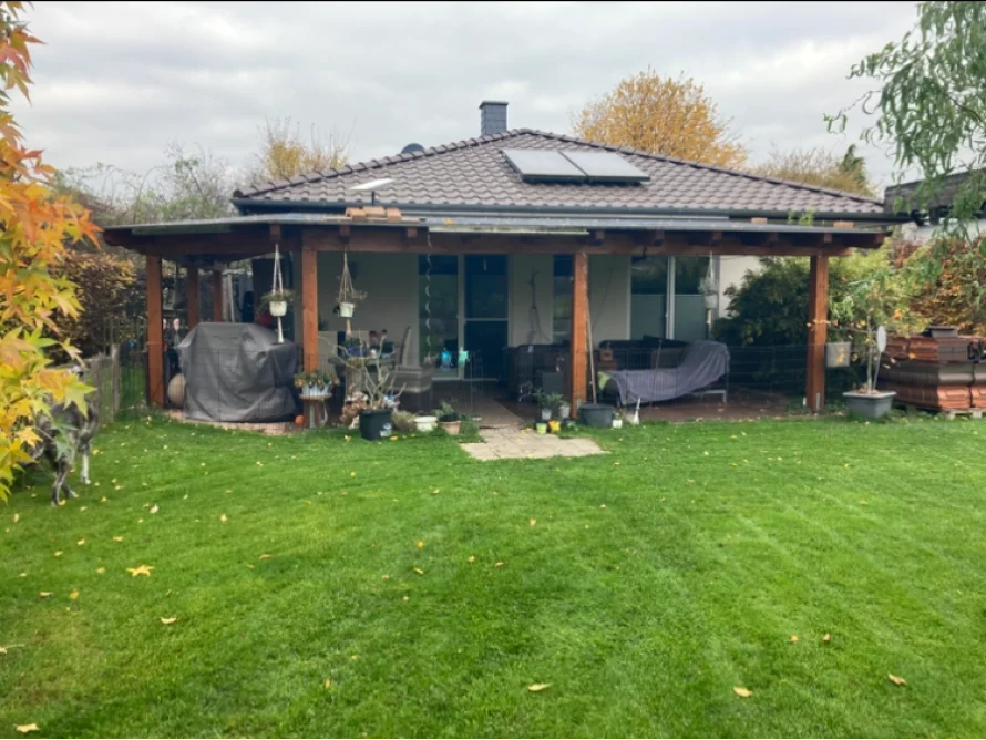 Gartenhaus mit überdachter Terrasse und grünem Rasen