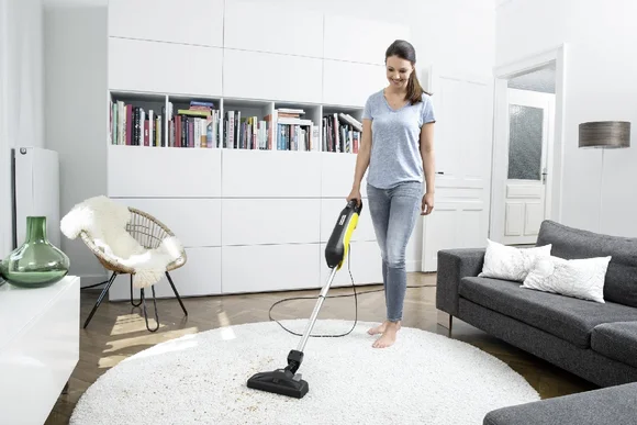Person saugt Teppich mit Staubsauger
