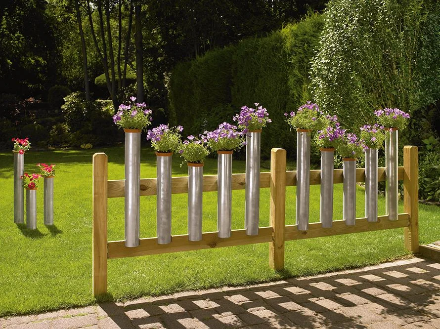 Blumenkästen aus Rohren an einem Holzzaun