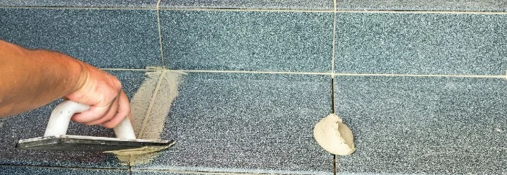 Person verfugt Fliesen auf einer Treppe.