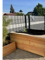 Schwarze Badewanne auf Holzpodest im Garten