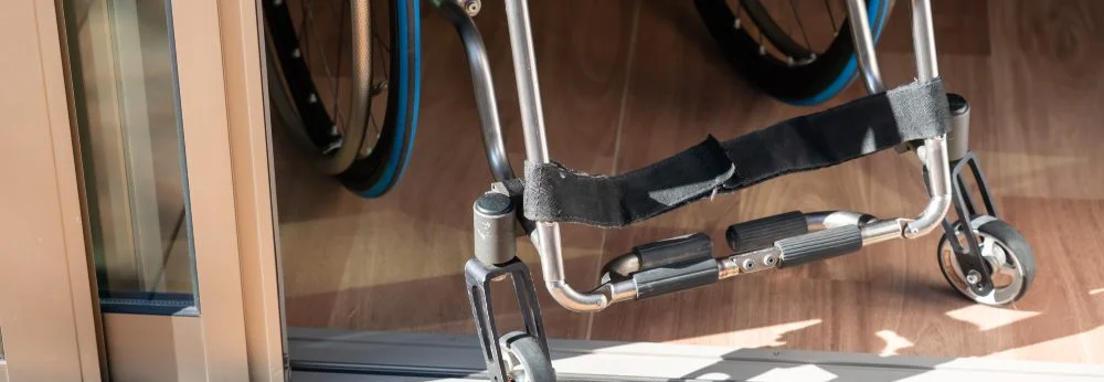 Nahaufnahme eines Rollstuhls an einer barrierefreien Türschwelle zur Terrasse.