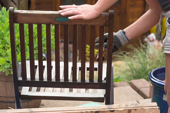 Person streicht Gartenstuhl mit Pinsel