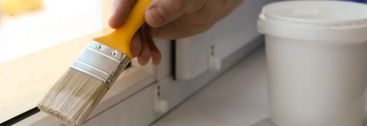 Hand streicht Fensterrahmen weiß