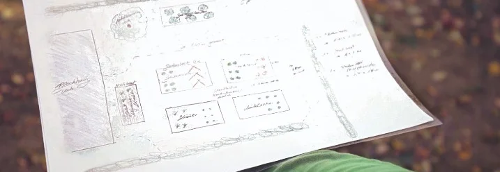 Eine Hand hält einen Gartenplan.