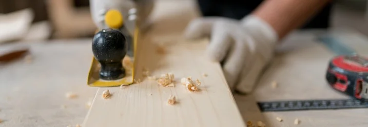 Person hobelt ein Holzbrett